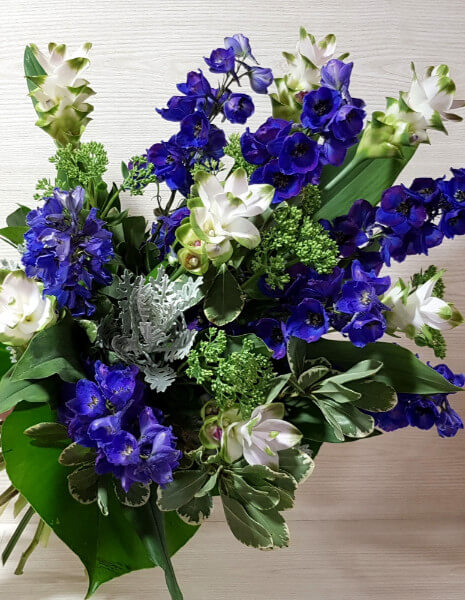 Mazzo fiori bianco e azzurro/blu con delphinium, curcuma e verdi decorativi