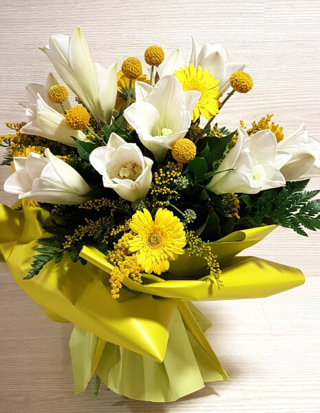 Mazzo di lilium bianco, gerbera gialla solidago e verdi decorativi